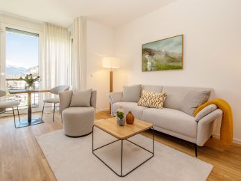 Schöne Wohnung mit weißer Couch, Holzboden und Blick auf Innsbruck